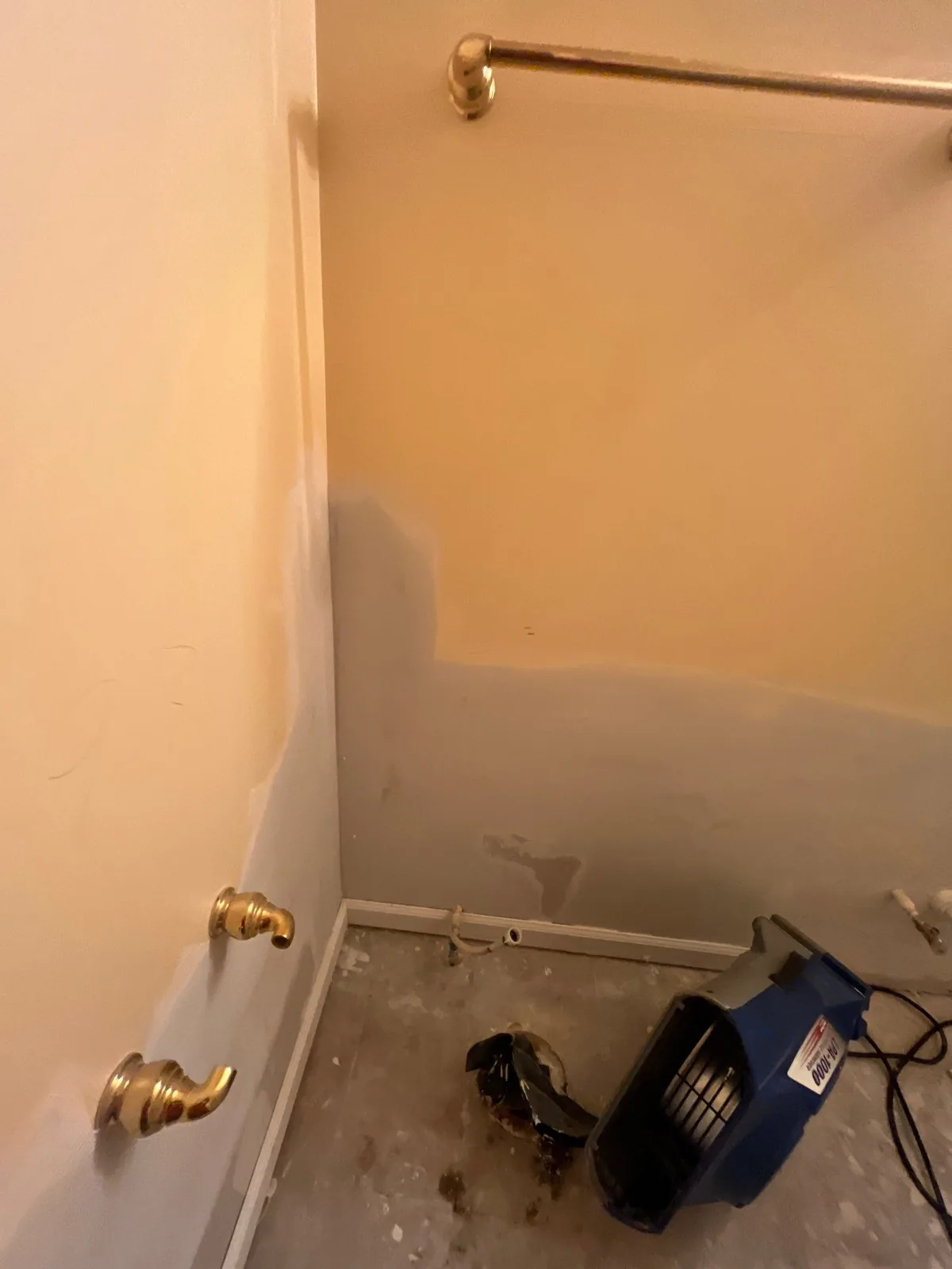 Bathroom with exposed drywall and a dehumidifier on the floor during water damage mitigation — serving Dallas, GA.