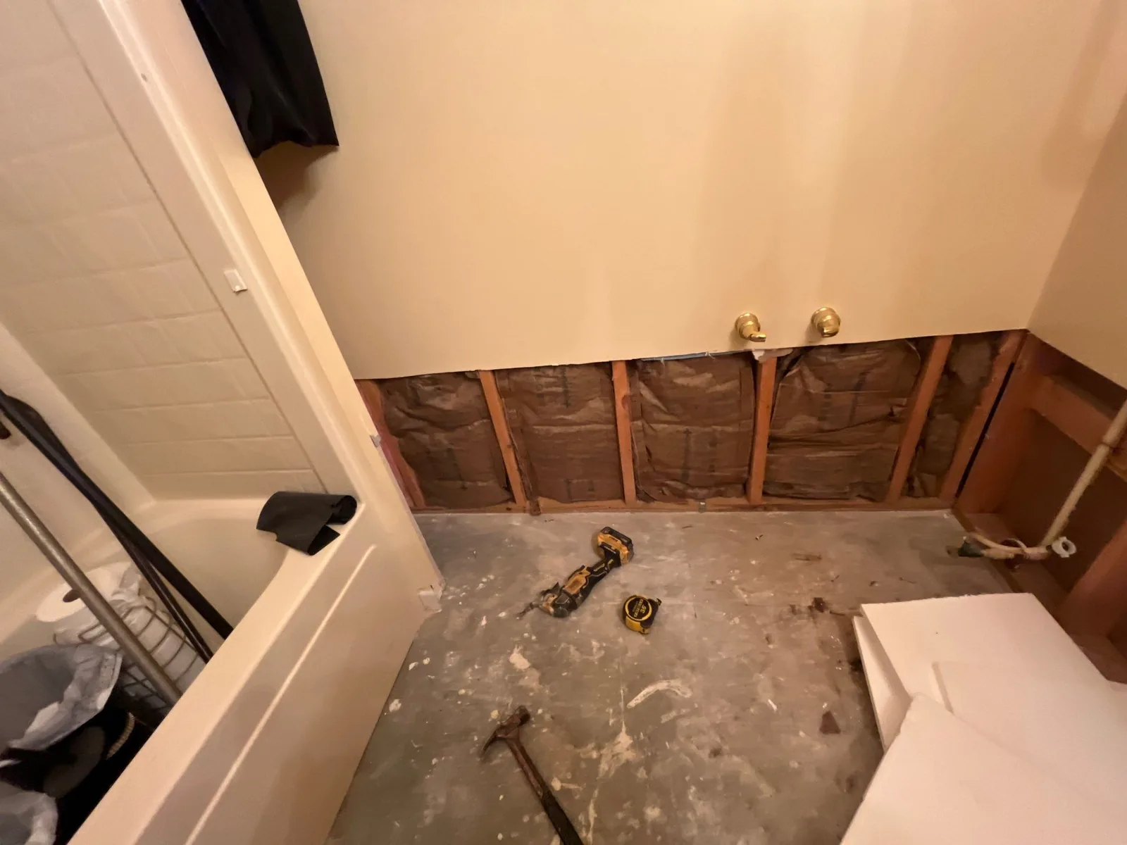 Bathroom renovation scene showing exposed wall with insulation, tools on the floor, and a bathtub on the left — serving Dallas, GA.