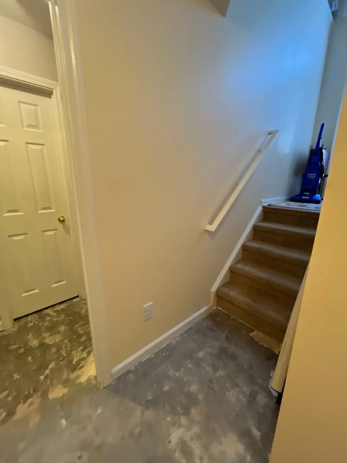 Staircase area with unfinished concrete floor and a vacuum cleaner on the stairs, suggesting a restoration phase — serving Dallas, GA.