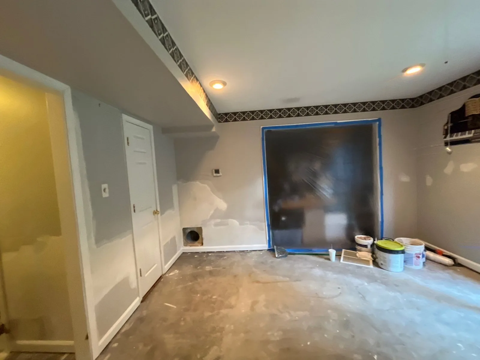 Room under restoration with patched walls, unfinished floor, and buckets near a plastic-covered window — serving Dallas, GA.