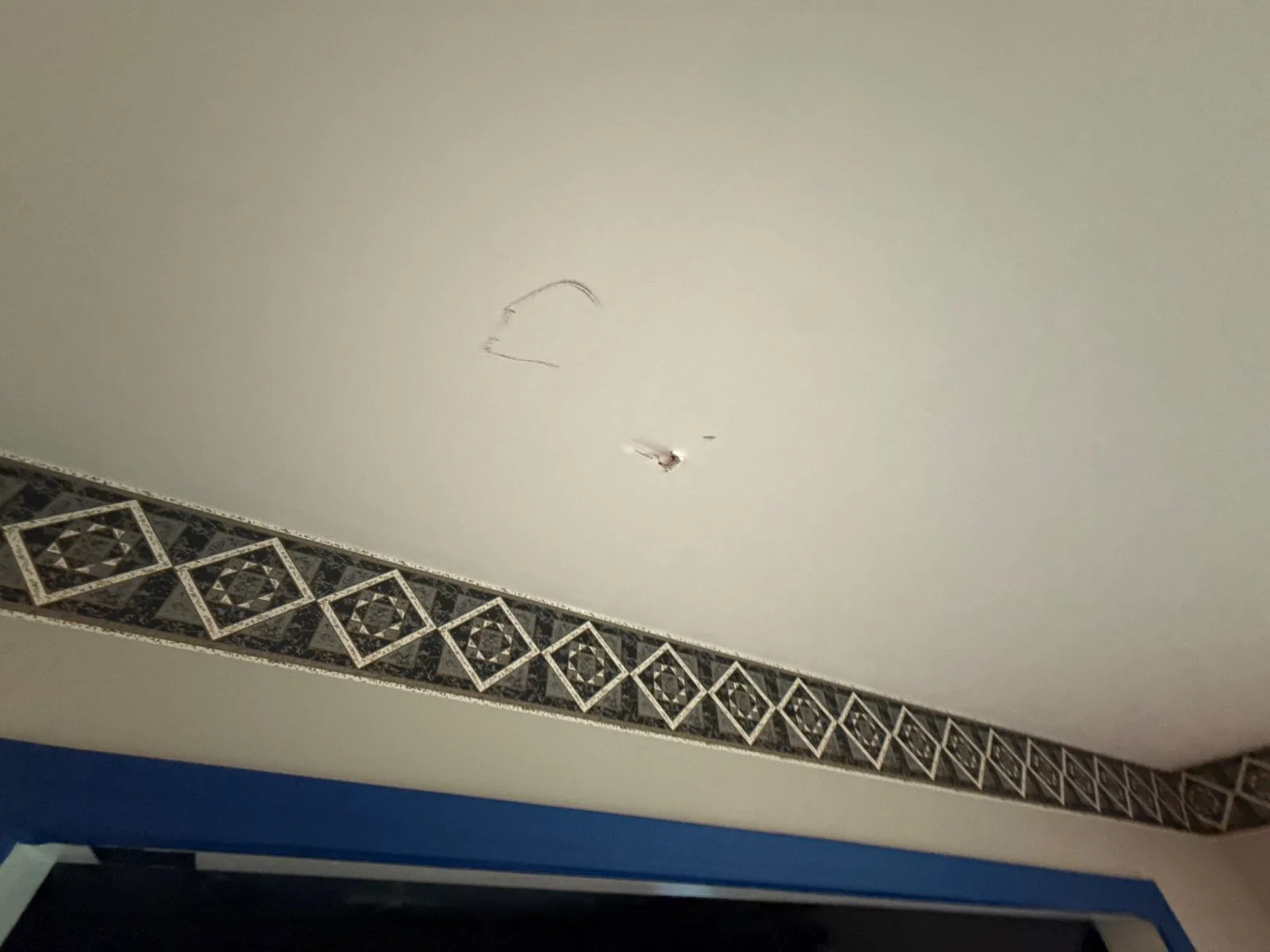 Ceiling with damage, patterned border, and blue trim visible — serving Dallas, GA.