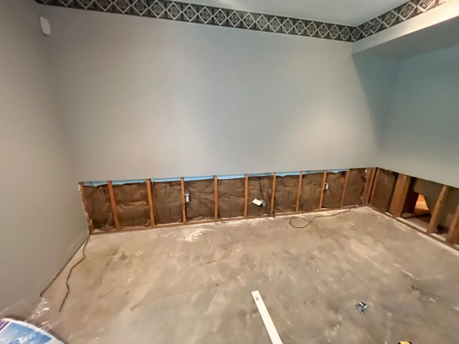 Interior of a room with sections of the lower wall removed, exposing insulation and wiring as part of water mitigation work — serving Dallas, GA.