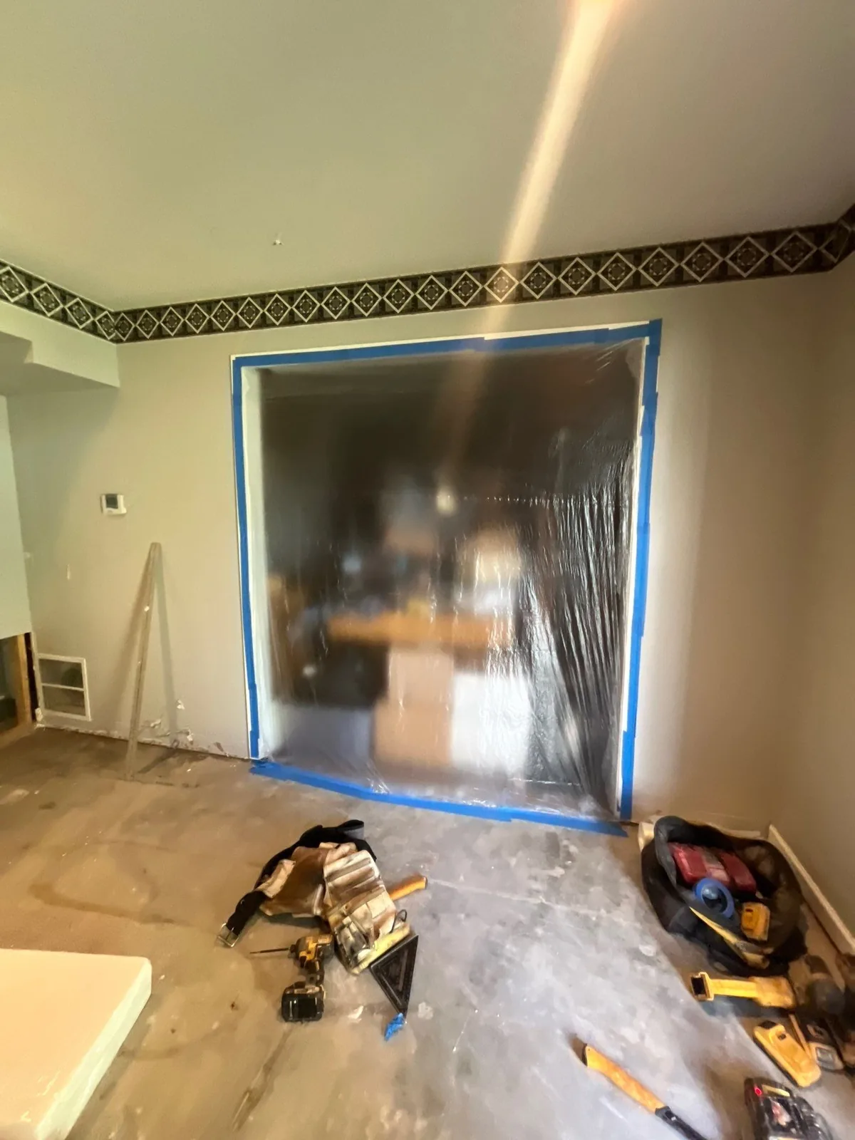 Room under renovation with plastic sheeting over an opening and construction tools on the floor — serving Dallas, GA.
