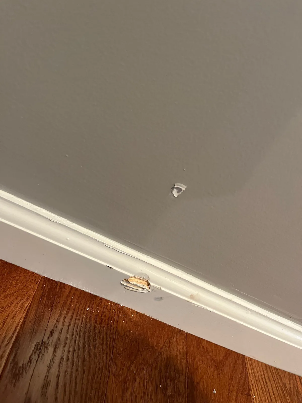 Baseboard with chipped paint and wall dent in a home interior — serving Dallas, GA.