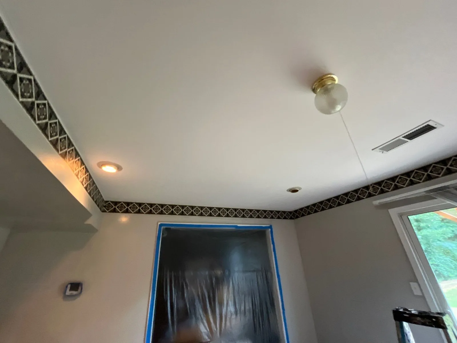 Interior room renovation with protective plastic sheeting over a door, decorative trim on walls, and ceiling work in progress — serving Dallas, GA.