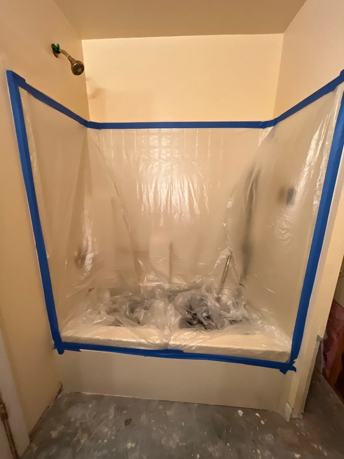 A bathtub in a bathroom is covered with plastic sheeting and blue tape as part of water mitigation efforts — serving Dallas, GA.