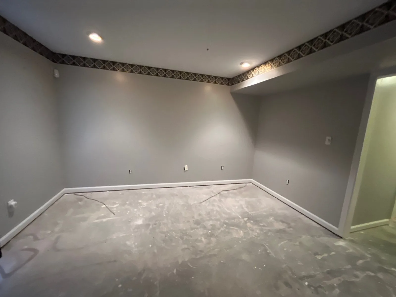 A room with gray walls, missing baseboards, and an unfinished floor, during construction — serving Dallas, GA.