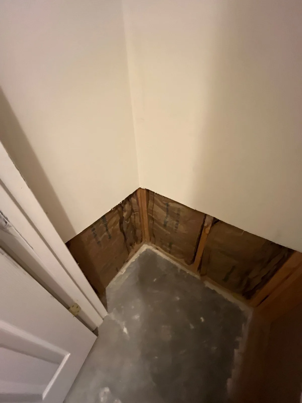 Exposed wall insulation and concrete floor in a room corner, with drywall removed — serving Dallas, GA.