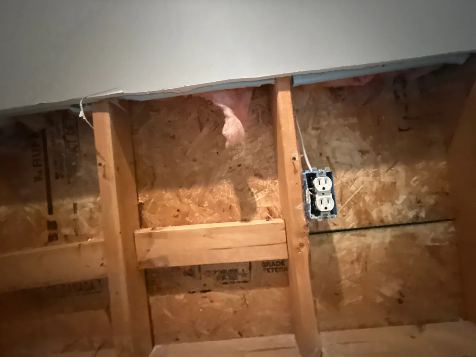 Exposed wall with electrical outlet, wooden studs, and insulation visible — serving Dallas, GA.