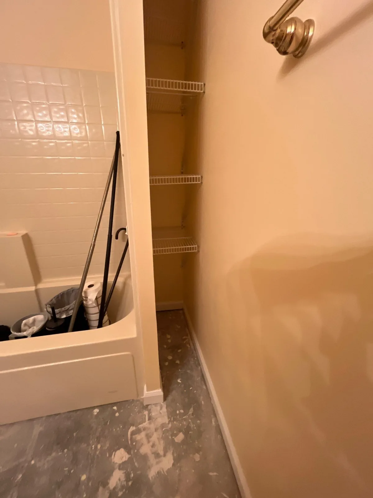 Bathroom showing a tub with tools, wire shelving, and unfinished flooring during renovation — serving Dallas, GA.