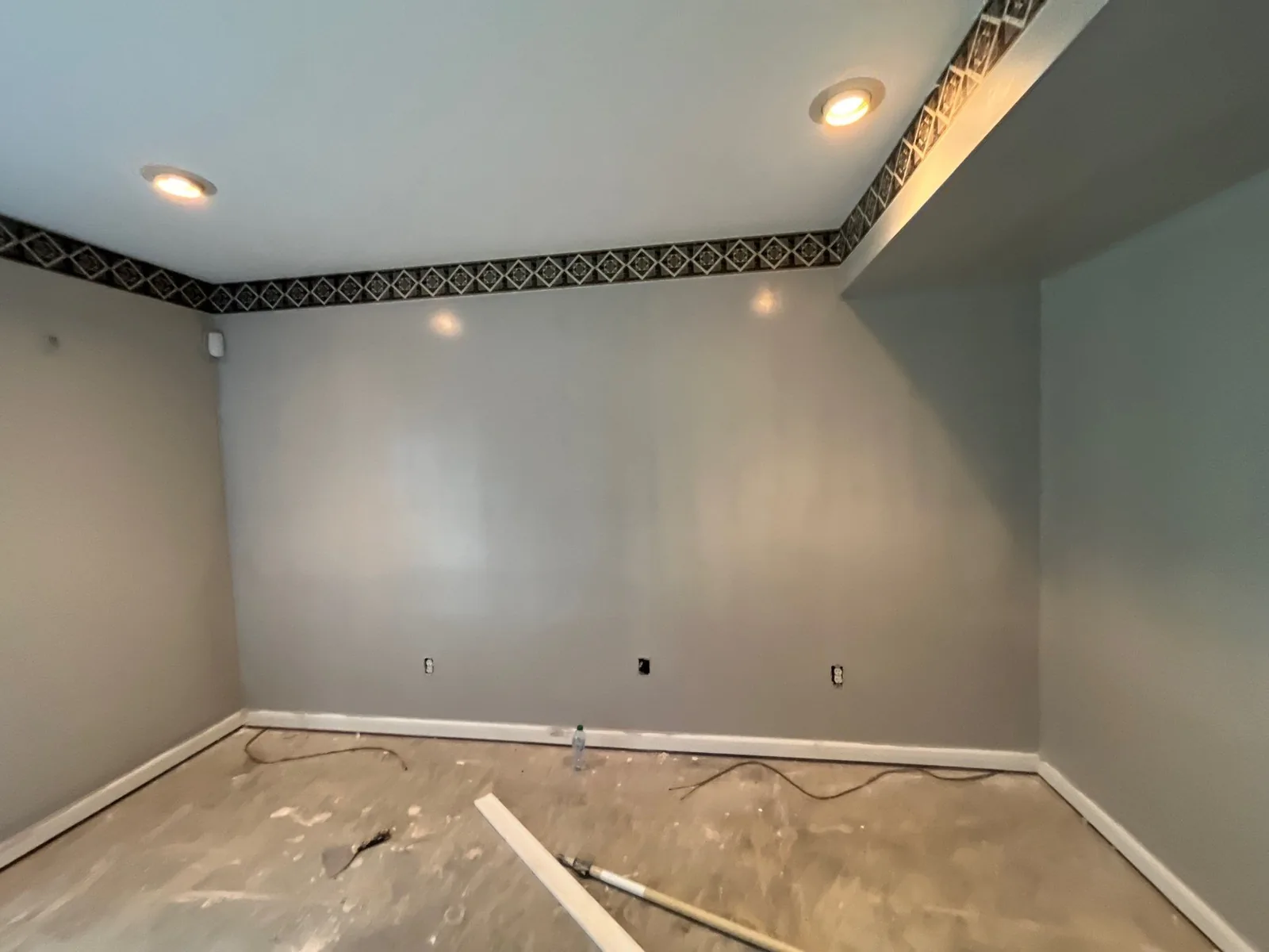 Room under renovation with painted walls, recessed lighting, and a decorative border. The floor is unfinished — serving Dallas, GA.