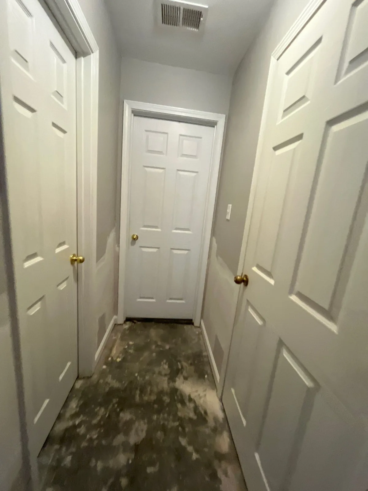 Hallway with multiple white doors and visible drywall patches, showing signs of ongoing construction or restoration work — serving Dallas, GA.