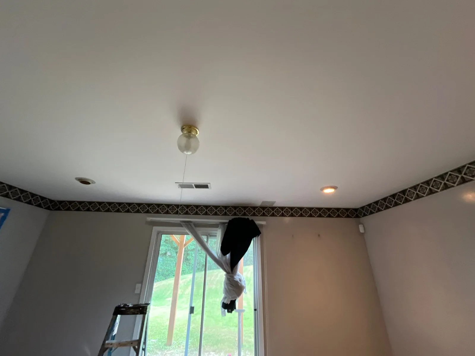 Interior room with step ladder and plastic-covered window, showing partially completed drywall work — serving Dallas, GA.