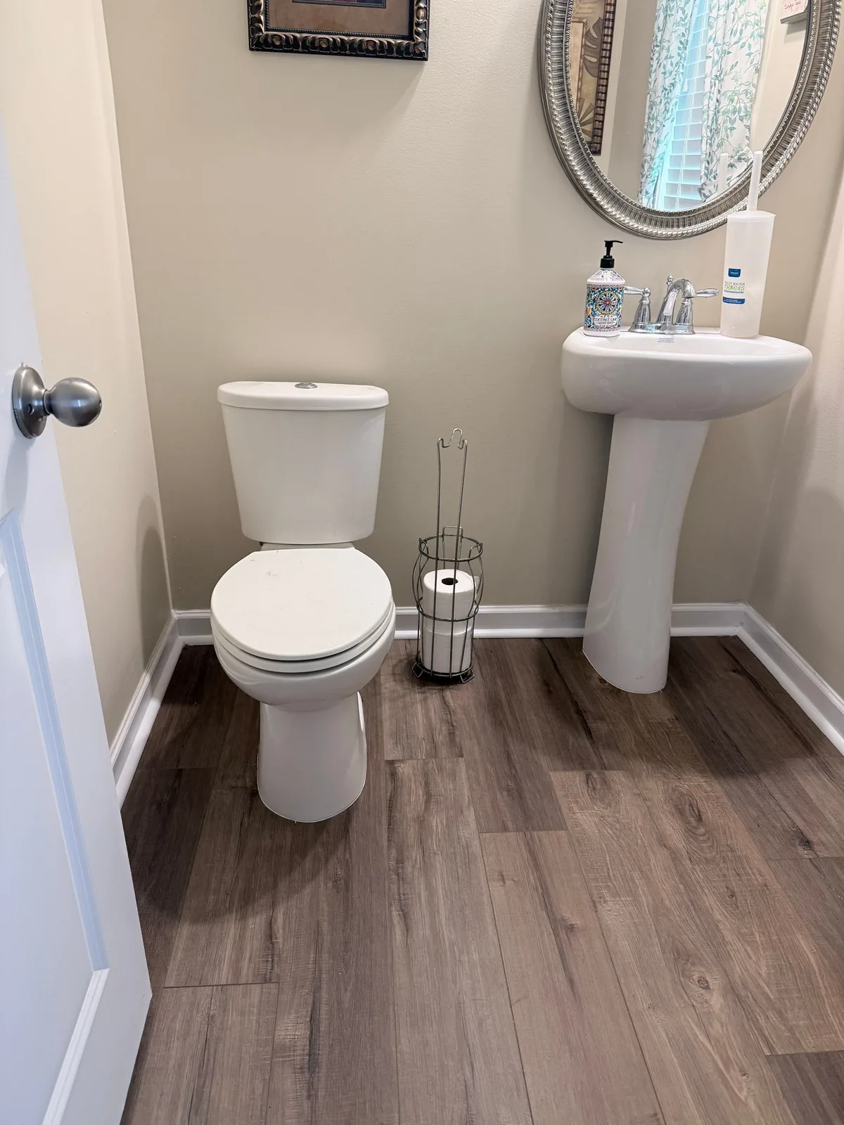 Bathroom with new toilet, pedestal sink, and wood-look flooring after remodeling — serving Dallas, GA.