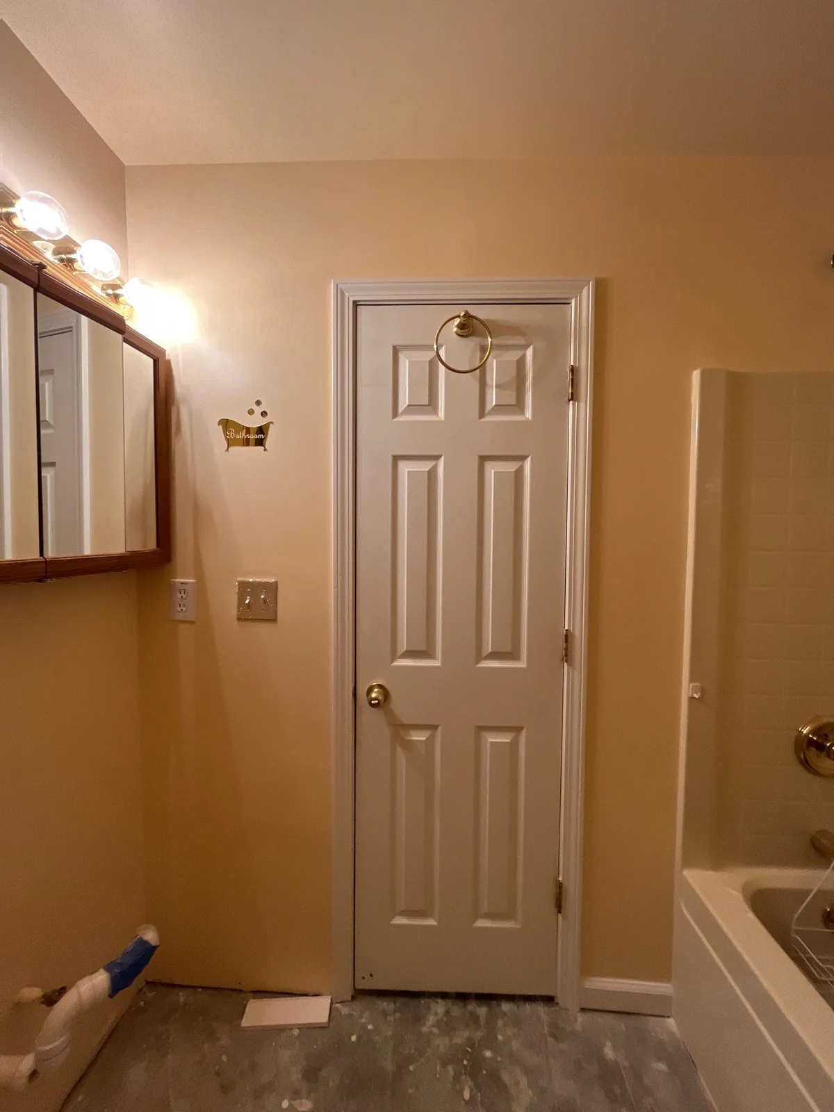 Partially remodeled bathroom with door, vanity mirror with lights, exposed pipes, and a bathtub — serving Dallas, GA.