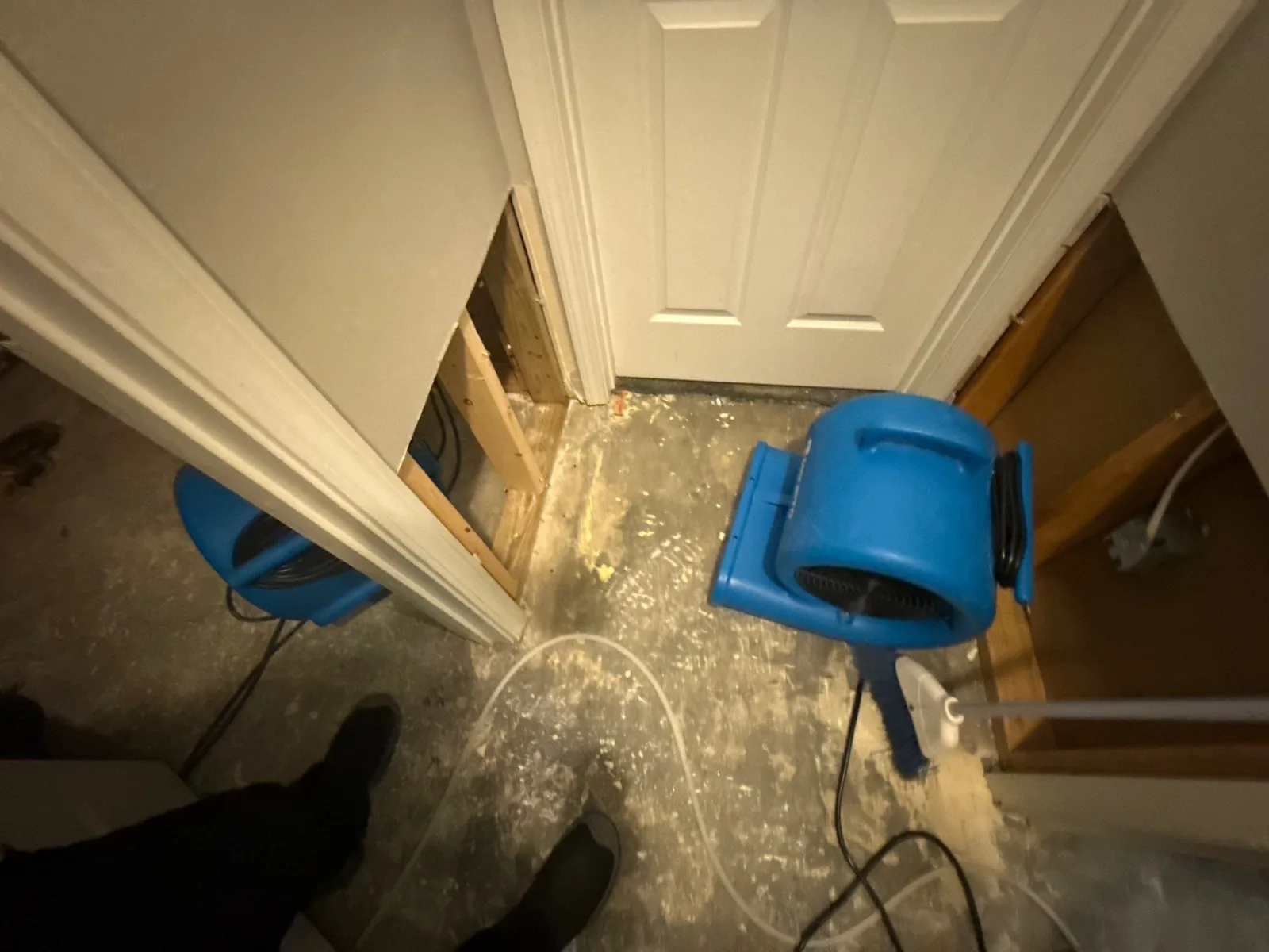 Room in water mitigation phase with two blue air movers on the floor and partially opened walls for drying — serving Dallas, GA.