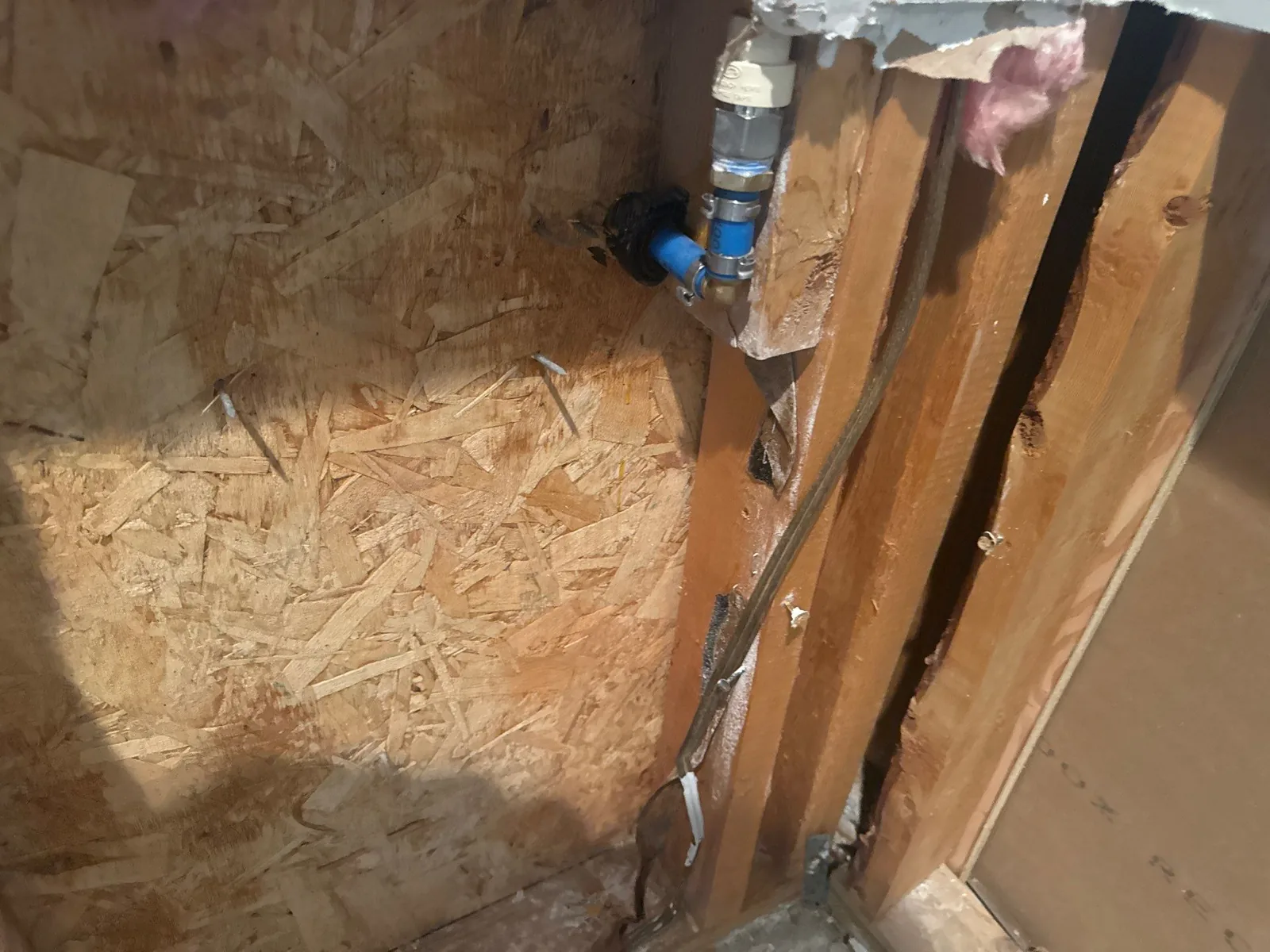 Exposed wall area with wood framing, plumbing pipes, and pink insulation — serving Dallas, GA.