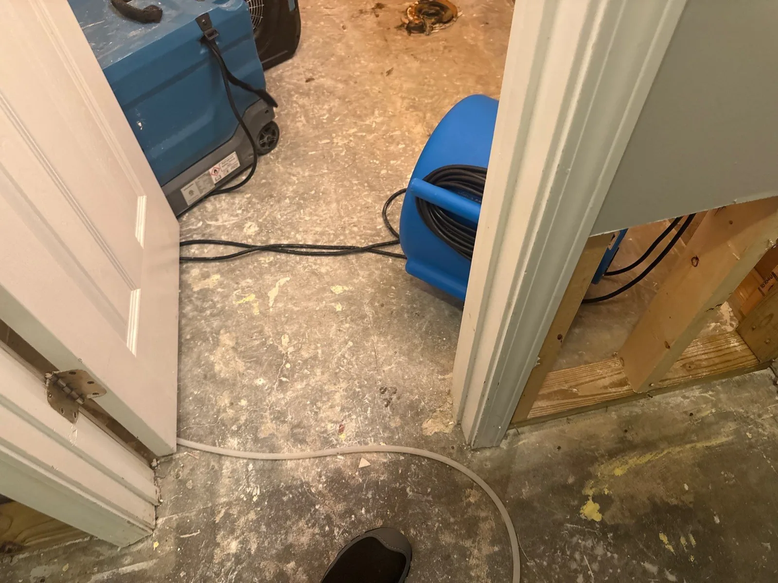 Room with exposed subfloor showing water mitigation equipment like air blowers and dehumidifiers — serving Dallas, GA.