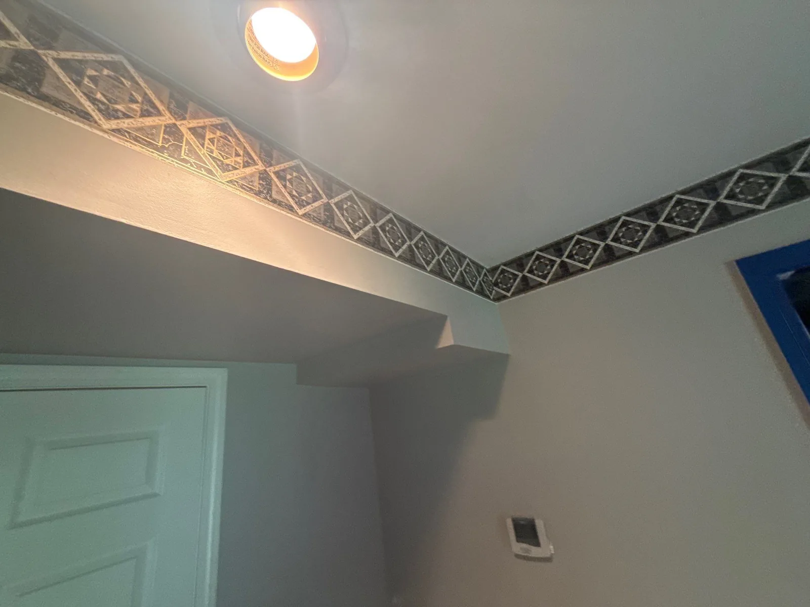 Room corner featuring patterned border, recessed ceiling light, and wall-mounted thermostat — serving Dallas, GA.