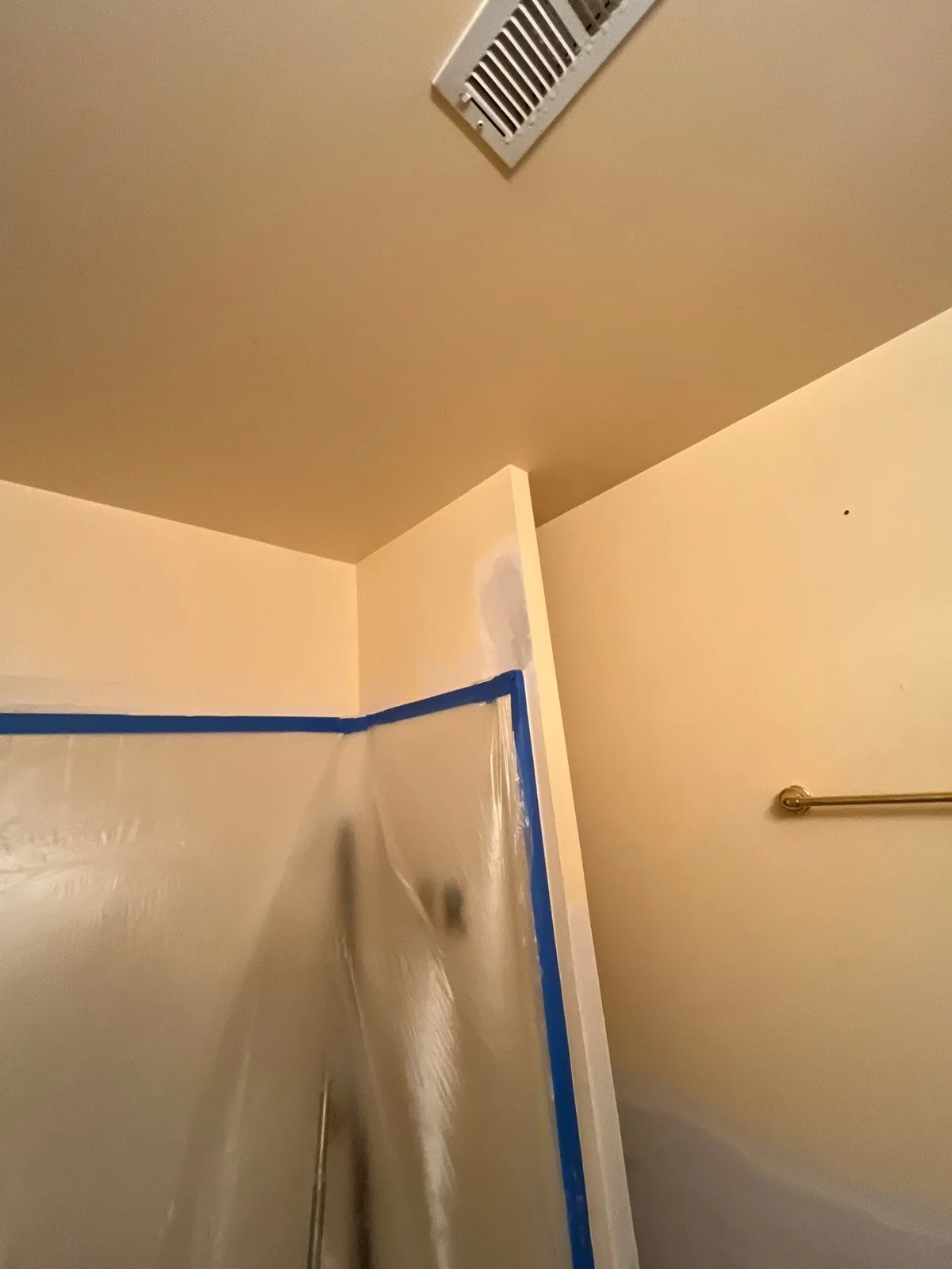 Bathroom renovation showing an air vent, plastic sheeting taped to the wall, and a towel rack — serving Dallas, GA.