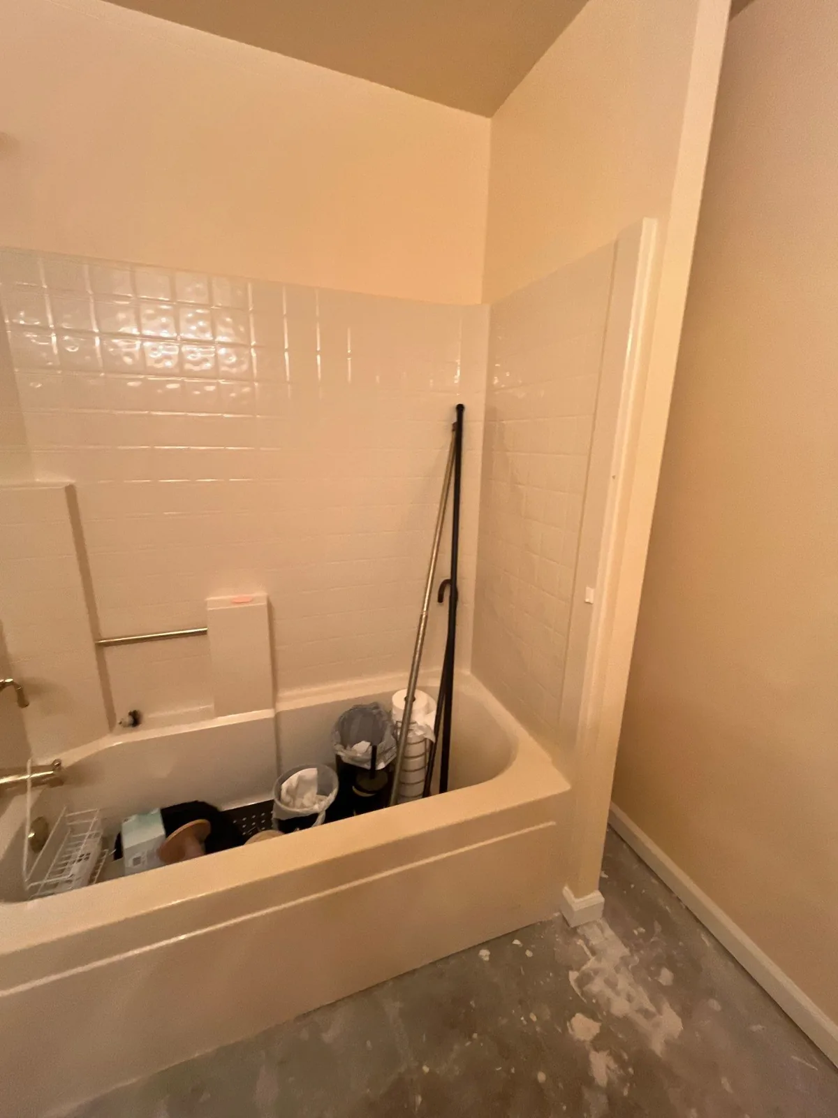 Bathroom renovation showing a tub filled with cleaning tools and materials, with partially finished flooring — serving Dallas, GA.