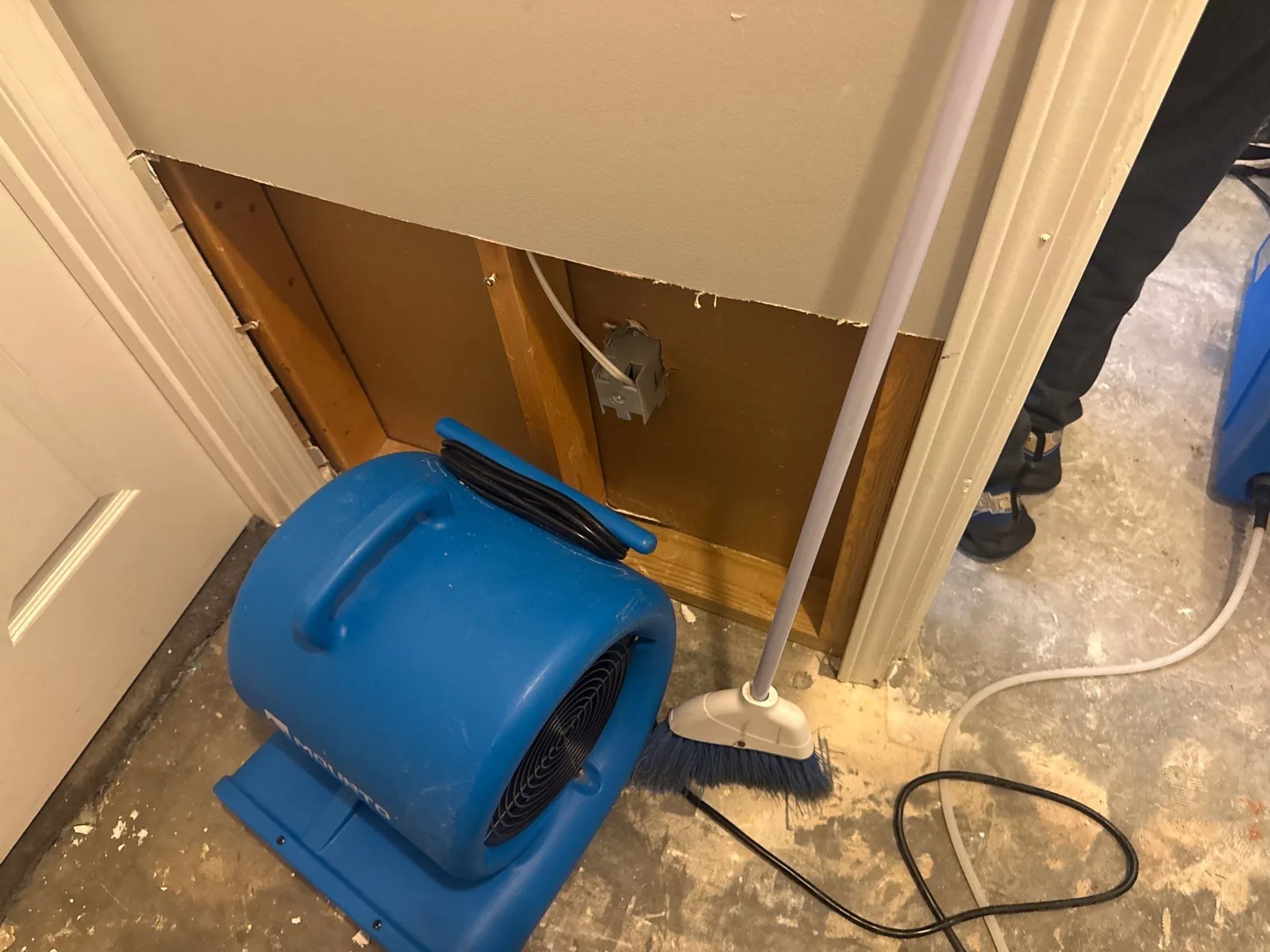 Blue air mover and broom in a room with partial wall removal for water mitigation — serving Dallas, GA.