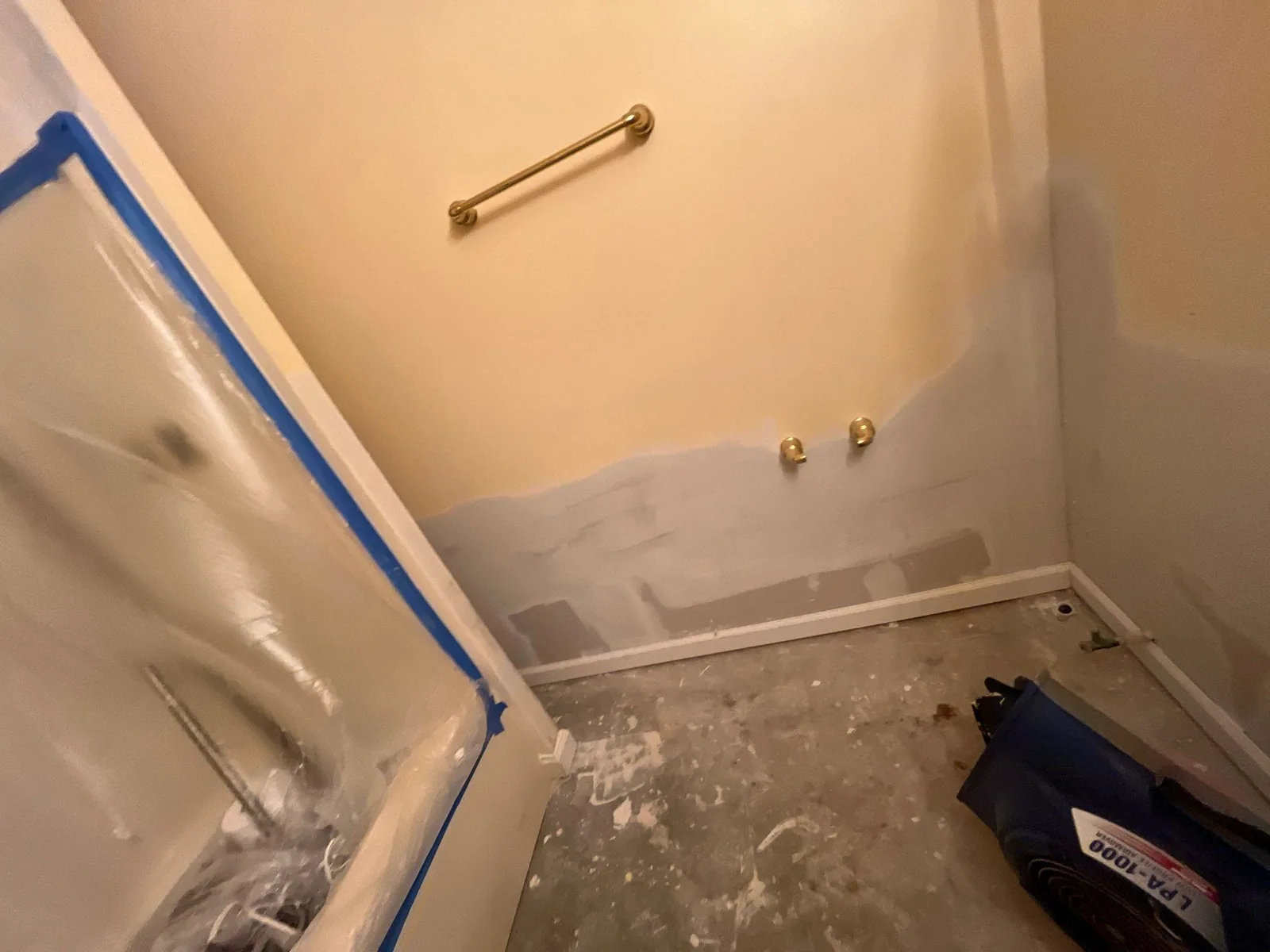 Bathroom under renovation with exposed flooring, partially painted walls, and a covered bathtub — serving Dallas, GA.