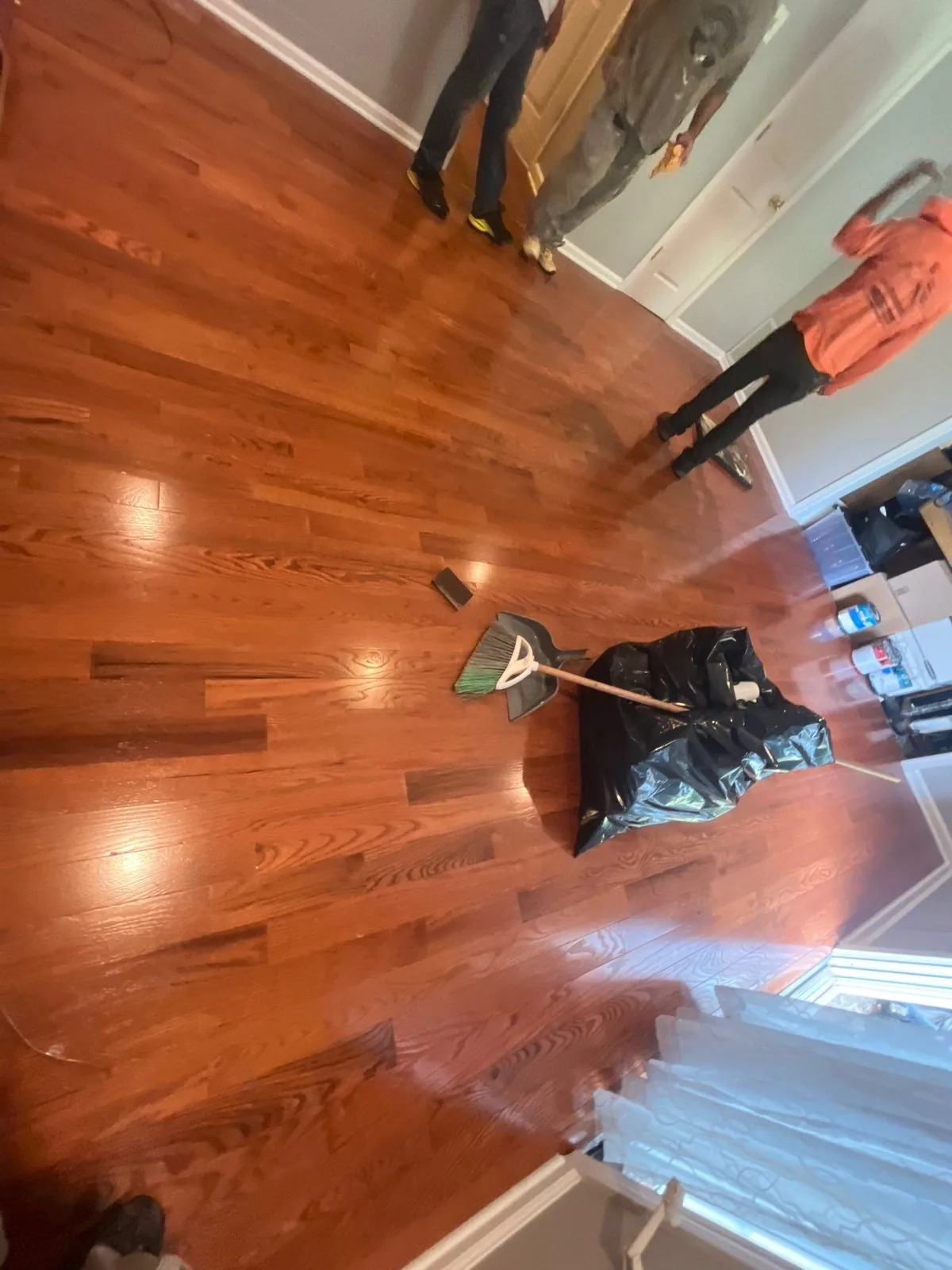 Completed hardwood floor renovation with broom and mop in a room with neutral walls — serving Dallas, GA.