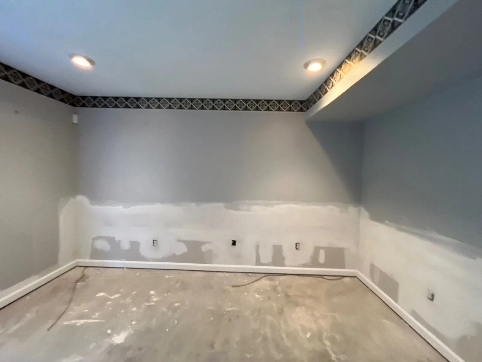 Room under construction with drywall compound on walls, recessed lights, and bare floor — serving Dallas, GA.