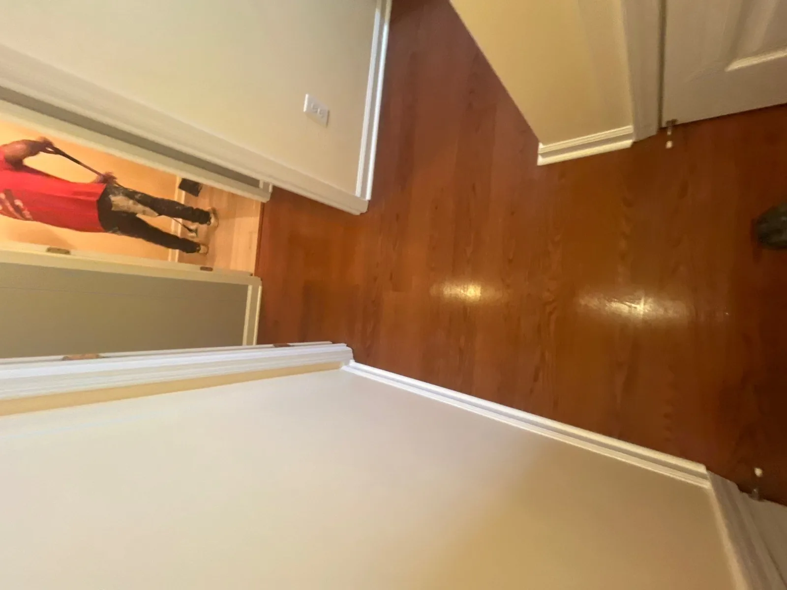 Completed hardwood flooring in a hallway with a person working in the background — serving Dallas, GA.