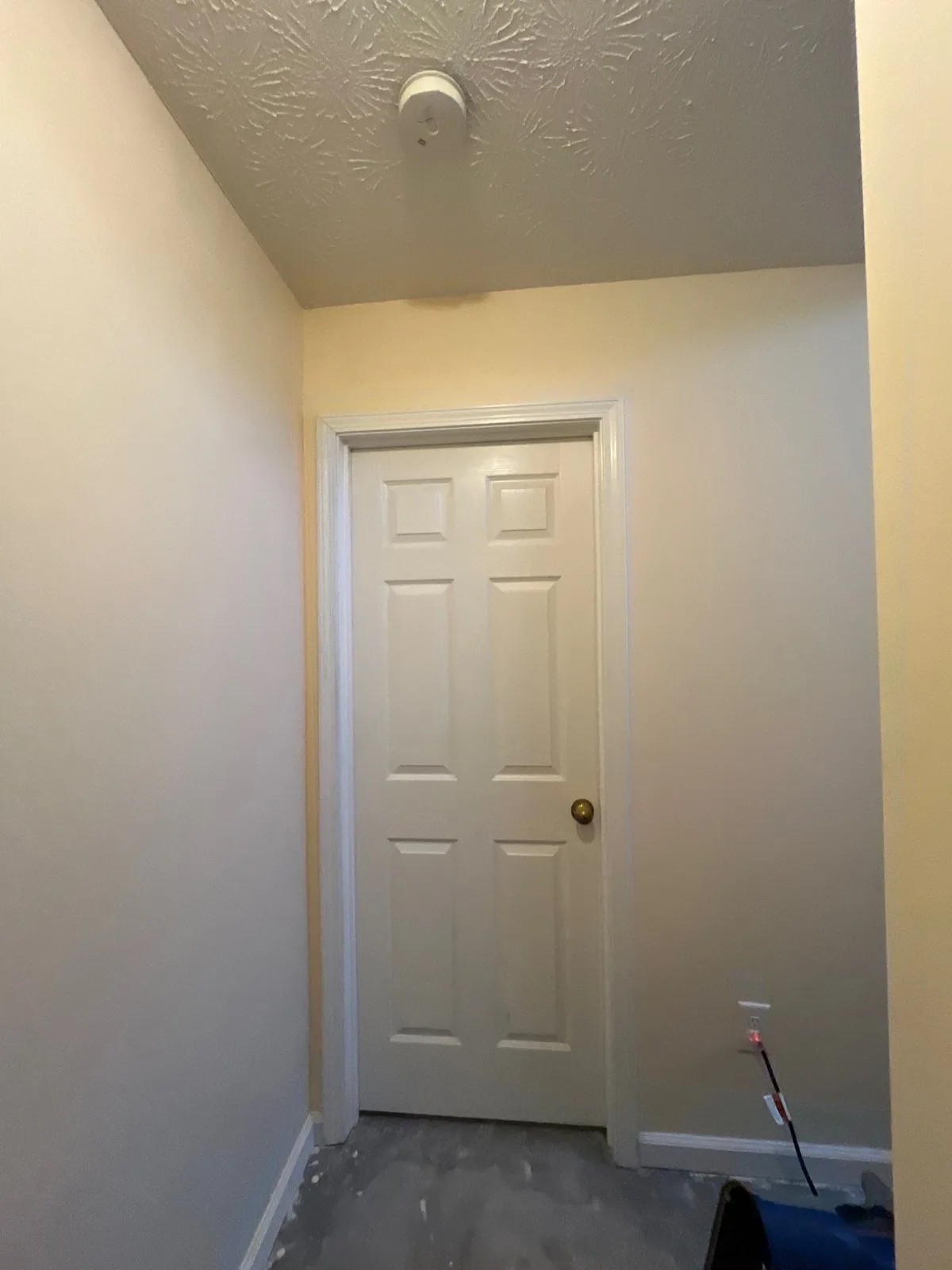 Image of a hallway under construction with a closed door, textured ceiling, and unfinished flooring — serving Dallas, GA.