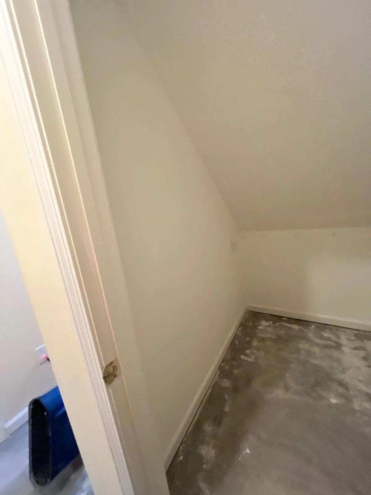 View of a small room with a sloped ceiling and unfinished concrete floor, seen through an open doorway — serving Dallas, GA.