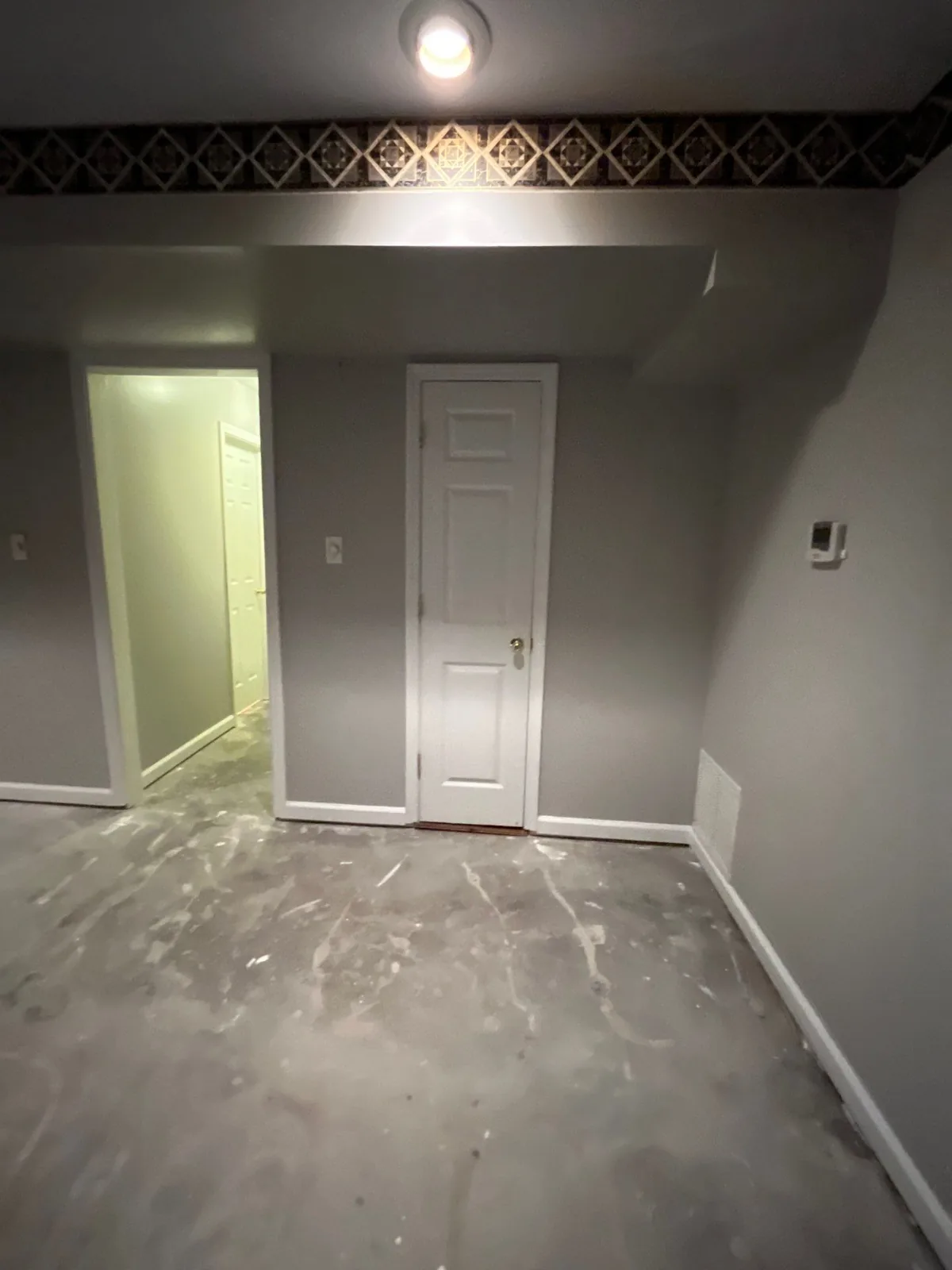 Room under renovation with gray walls, a main door, a smaller door, and an unfinished floor — serving Dallas, GA.
