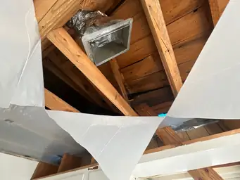Collapsed interior ceiling revealing wood roof rafters, exposed HVAC duct, and blown insulation from severe storm impact — Acworth, GA