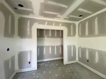 Basement drywall installation with joint compound taping on walls and coffered ceiling grid framing in bedroom — Metro Atlanta, GA