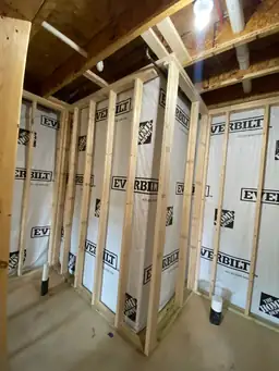 Basement bathroom rough-framing with Everbilt vapor barrier on stud walls, PVC drain pipes stubbed through slab — Metro Atlanta, GA