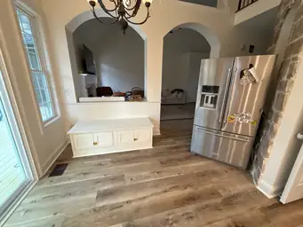 Kitchen renovation after — new hardwood floors, white bench cabinet with gold hardware, arched doorways — Powder Springs, GA