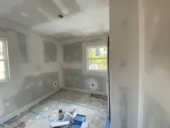 Interior bedroom with patched and primed drywall walls and two windows after drywall phase of home remodel — Marietta, GA