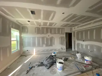 Basement drywall finishing with joint compound coats on walls and coffered ceiling, work tools on concrete floor — Metro Atlanta, GA