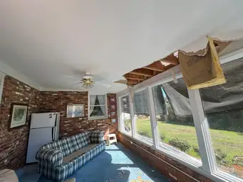 Sunroom before water damage assessment with ceiling torn open at corner exposing rotted roof sheathing — Marietta, GA