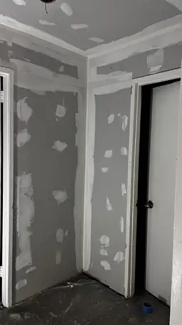 New drywall installed on hallway walls and ceiling with joint compound spot patches during storm damage repair — Acworth, GA