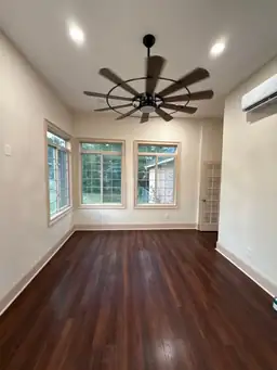Completed sunroom interior with dark hardwood floors, multi-pane windows flanking walls, and ductless mini-split unit — Marietta, GA