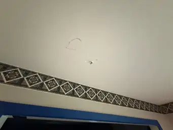 Ceiling with damage, patterned border, and blue trim visible — serving Dallas, GA.
