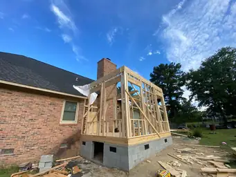 Interior view of sunroom addition roofline framing with exposed rafters and plywood sheathing looking outward during construction — Marietta, GA