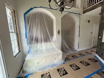 Dining area during renovation — new chandelier installed, arched openings prepped and protected, floors covered — Powder Springs, GA