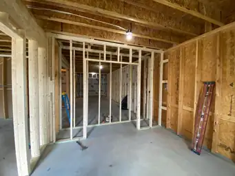 Basement construction with interior wood stud partitions, OSB sheathing, ladder and tools staged on concrete slab — Metro Atlanta, GA