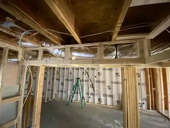 Basement framing with Everbilt vapor barrier on stud walls, flex HVAC ductwork overhead, and electrical rough-in — Metro Atlanta, GA