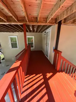 Lower covered porch with freshly stained red wood floor boards and exposed joist framing overhead during deck repair — Marietta, GA