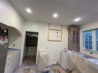 Kitchen renovation in progress — new recessed lighting installed in ceiling, lower cabinets wrapped in plastic, upper cabinet framing — Powder Springs, GA