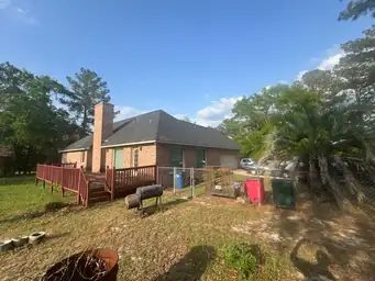 Completed rear deck with gray composite boards and white railing on brick home with sunroom addition exterior view — Marietta, GA